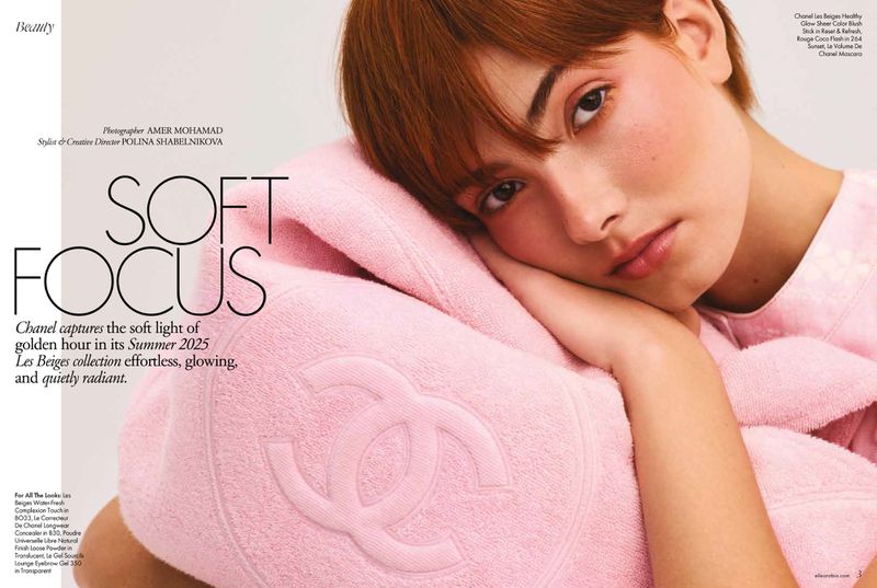 Portrait of a fair-skinned young woman with short brown hair leaning against a pink towel with a Chanel logo, beauty editorial.