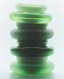A vertical stack of round translucent and frosted green glass rings backlit against a clean white luminous background.