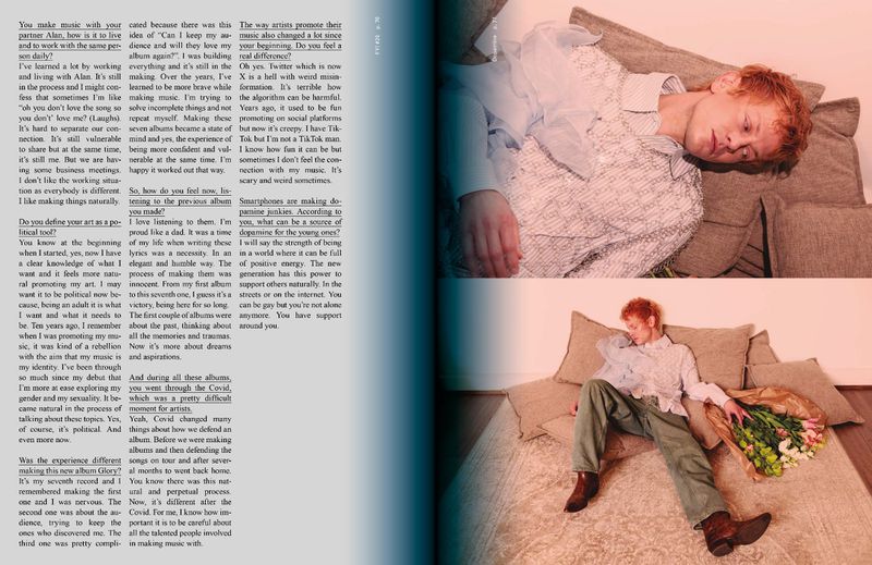 An editorial style studio shot showcases a red-haired person reclining on pillows next to a bouquet of flowers in an open magazine spread.