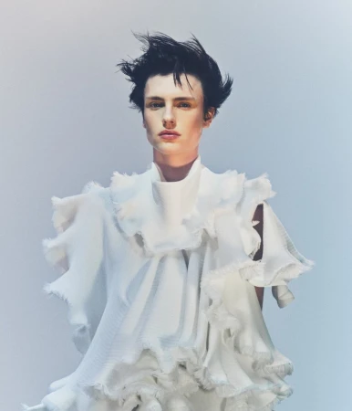 Model Charlie Jones wearing a sculptural white textured ruffled top against a pale cool-toned studio background.