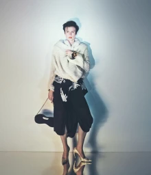 Model Charlie Jones in a chunky cream knit wrap, printed black skirt, and pointed heels against a studio backdrop.