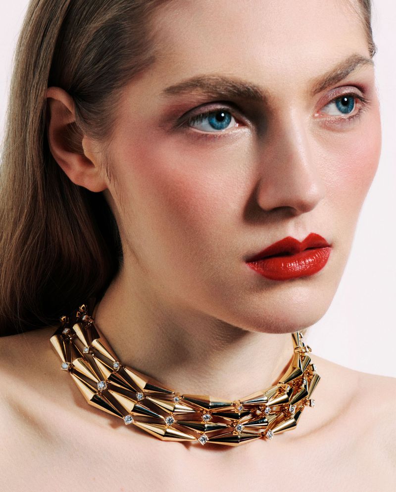 Close-up portrait of model Constanze Van Rosmalen wearing a multi-strand geometric gold choker necklace.