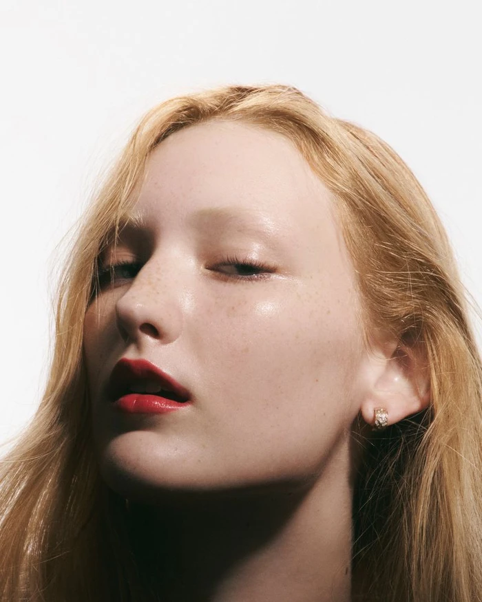 Close-up beauty portrait of a fair-haired woman with red lipstick against a plain white background