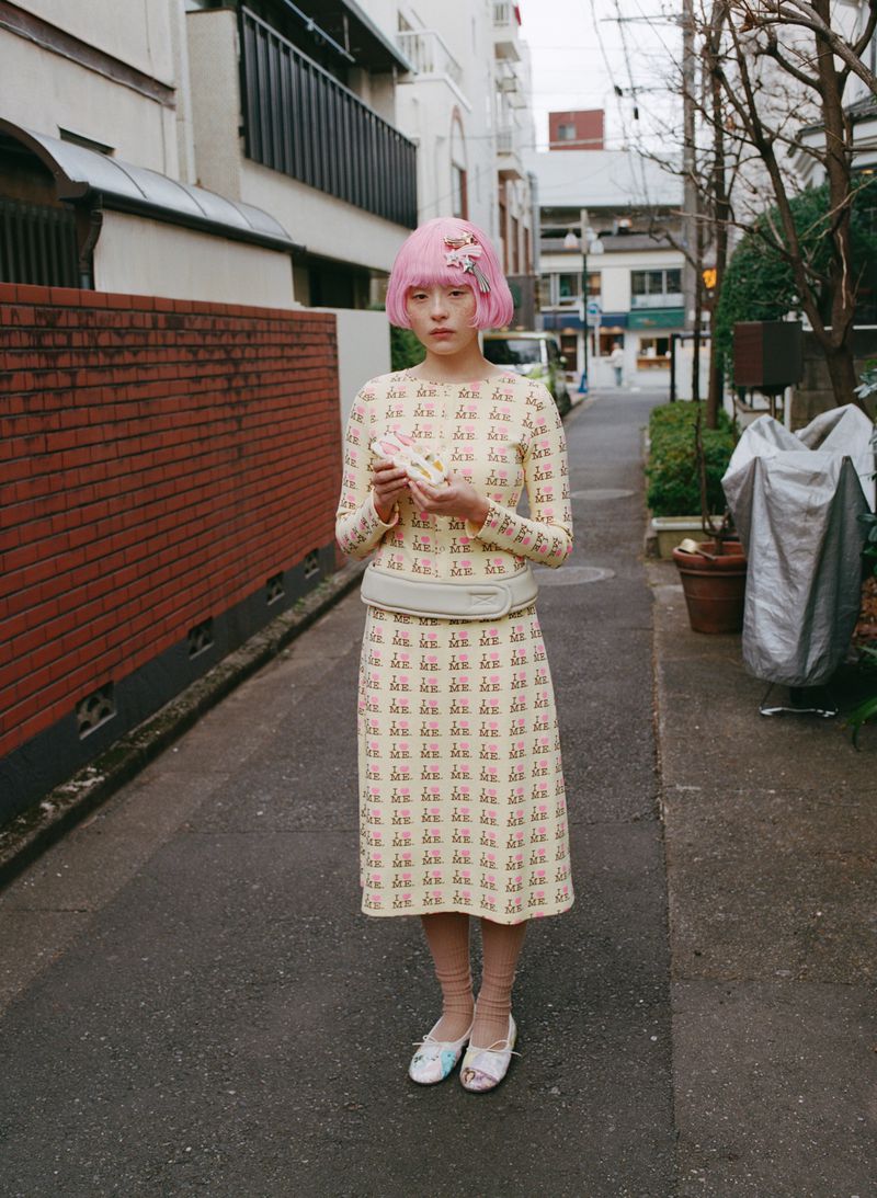 Serena Motola with a pink bob hairstyle wearing a patterned cream midi dress set on an urban street for Ashley Williams.