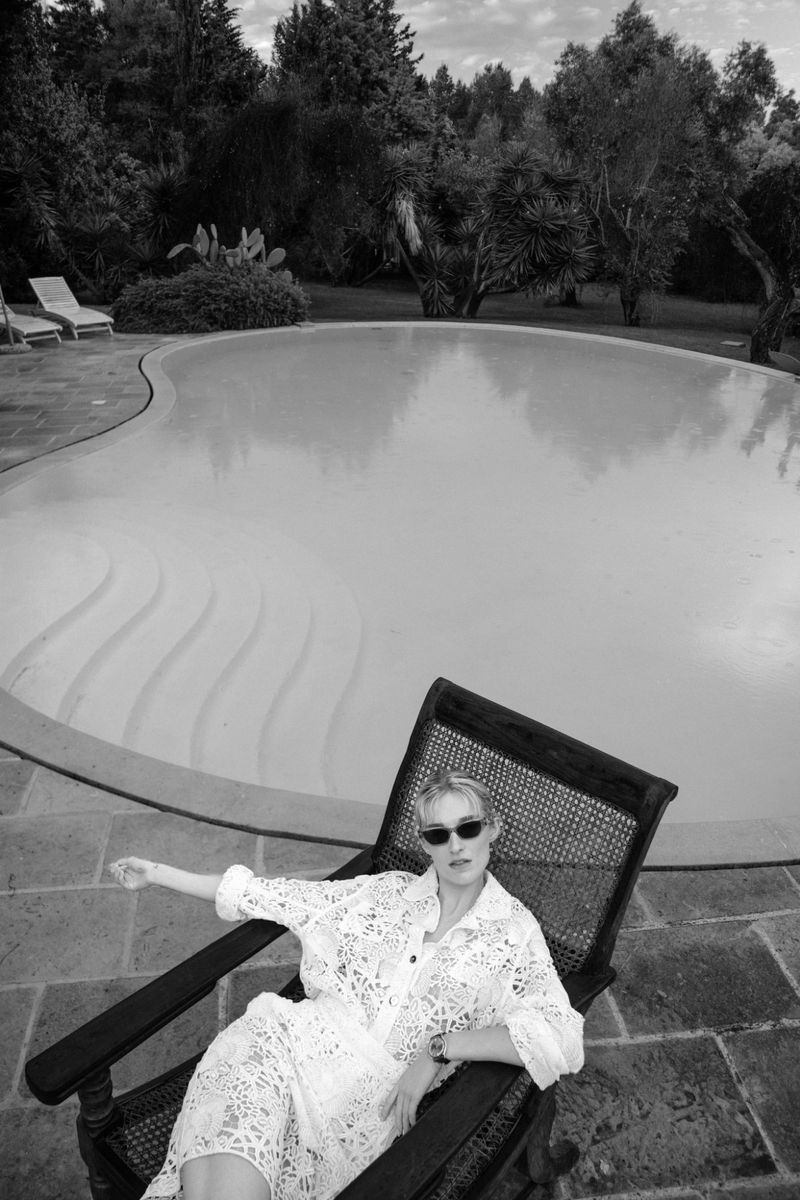 Model Manuela Frey wearing sunglasses and lace shirt seated in a poolside lounger for Schön! Switzerland la dolce vita
