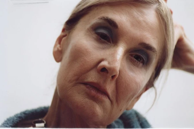 Close-up portrait of an older woman with blue eyeshadow against a plain white background for Hube Magazine.