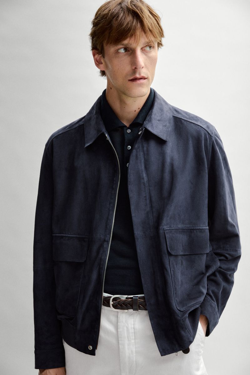 Model Quentin Demeester wears a navy jacket, dark polo, braided belt, and white trousers for Massimo Dutti.