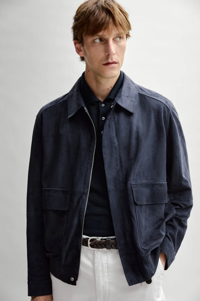 Model Quentin Demeester wears a navy jacket, dark polo, braided belt, and white trousers for Massimo Dutti.