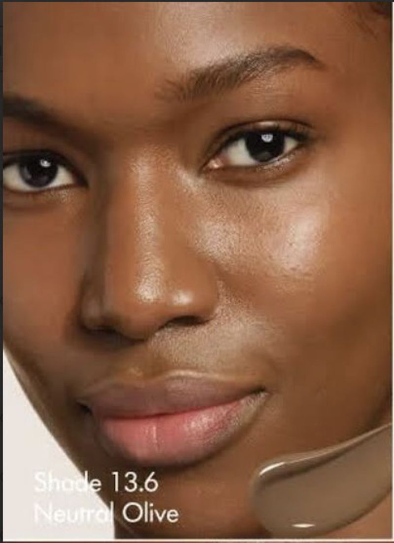 Close-up beauty portrait of model Tiah Beye showcasing radiant skin with a liquid foundation swatch.