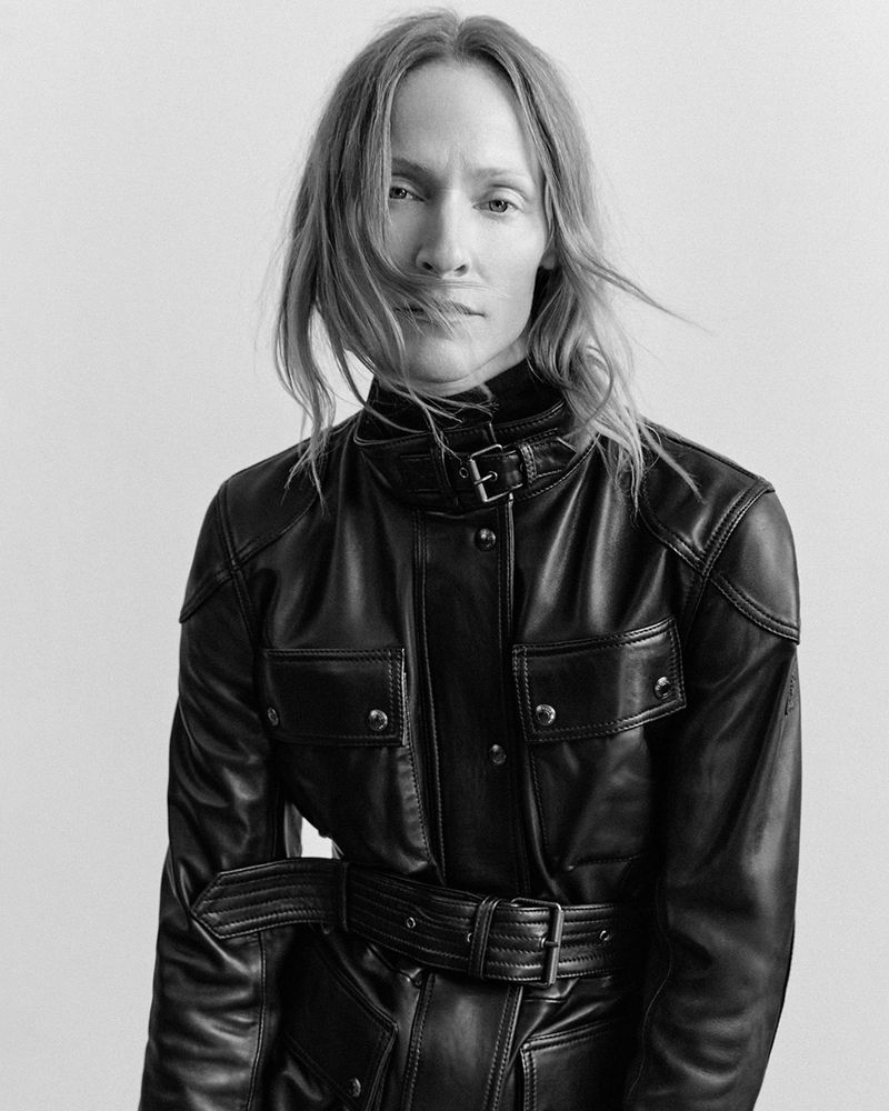 Model Lindsay Sullivan wearing a belted black leather motorcycle jacket in a black and white studio portrait.
