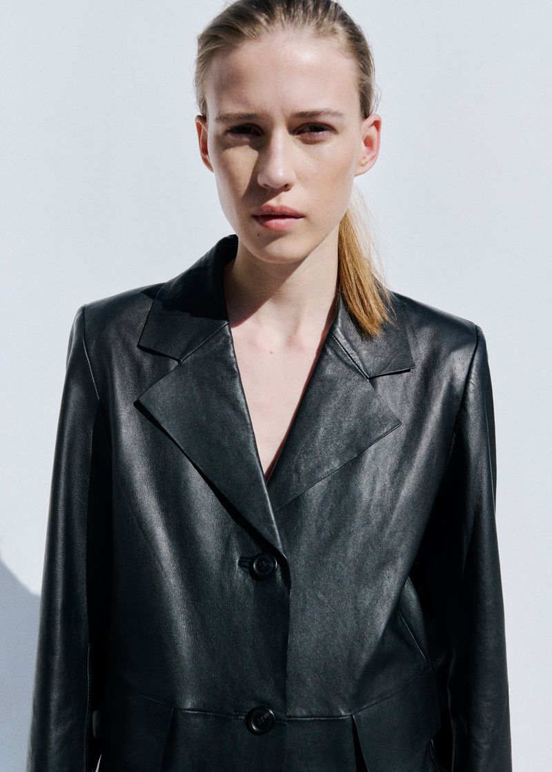 Model Liva Been wearing a tailored black leather blazer with notched lapels against a plain white studio backdrop.