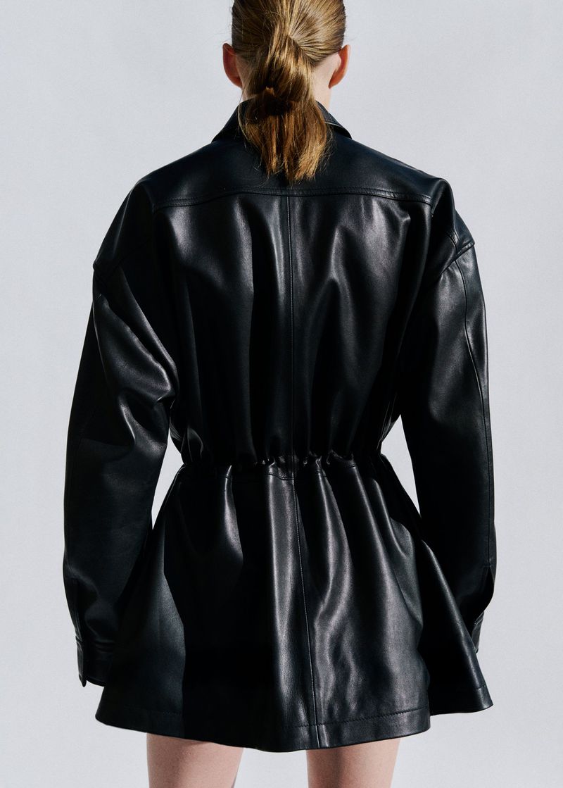 Model Liva Been seen from behind wearing a cinched black leather jacket against a light studio backdrop for Mango.