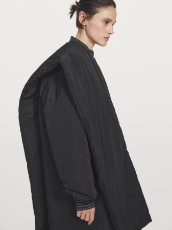 Model Aleyna Fitzgerald wearing an oversized black padded coat against a bright white background for Massimo Dutti
