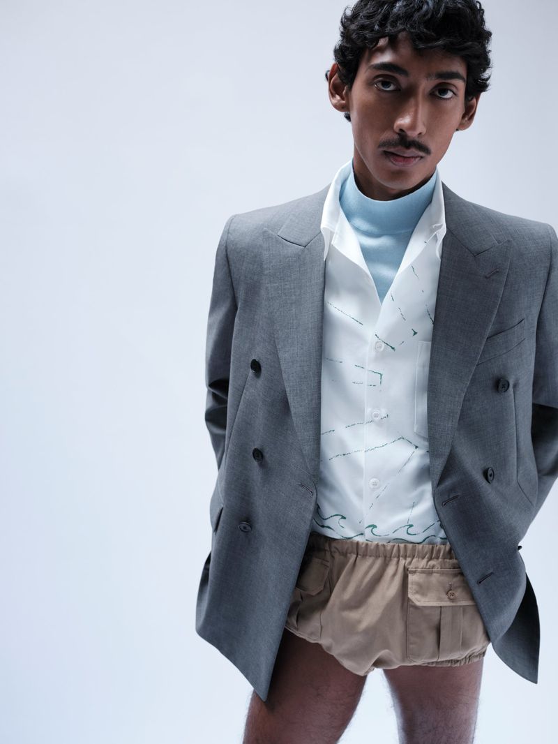 Model Viknes Waren wearing a grey double-breasted blazer and beige shorts against a white background
