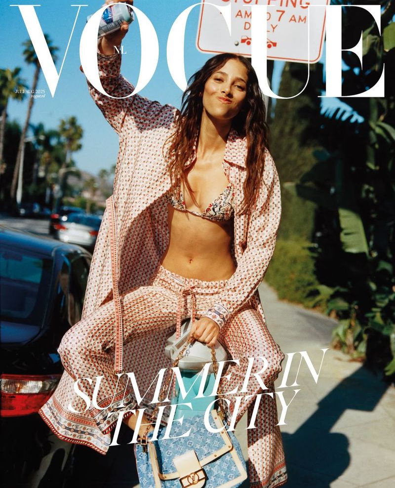 Vogue magazine cover featuring a woman in patterned resort wear, bikini top, and handbag, standing on a city street in sunny weather.