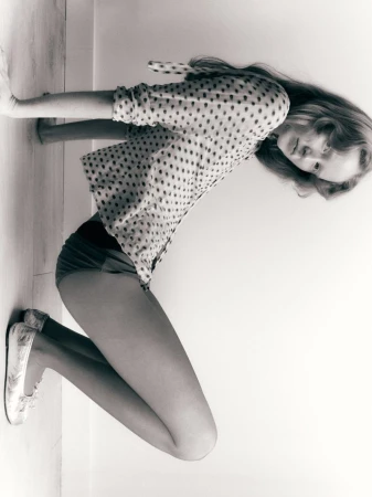 Model Lucy Arbuthnott crouching in a polka dot blouse and patterned ballet flats against a plain studio background.