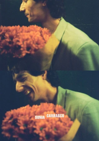 Model Noah Ramos smiles while holding a large bouquet of orange flowers for the Sonia Carrasco S/S 26 campaign.