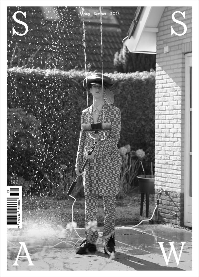 SSAW Magazine Spring/Summer 2026 cover showing a model in a patterned suit holding a broom amidst spraying water outside a house.