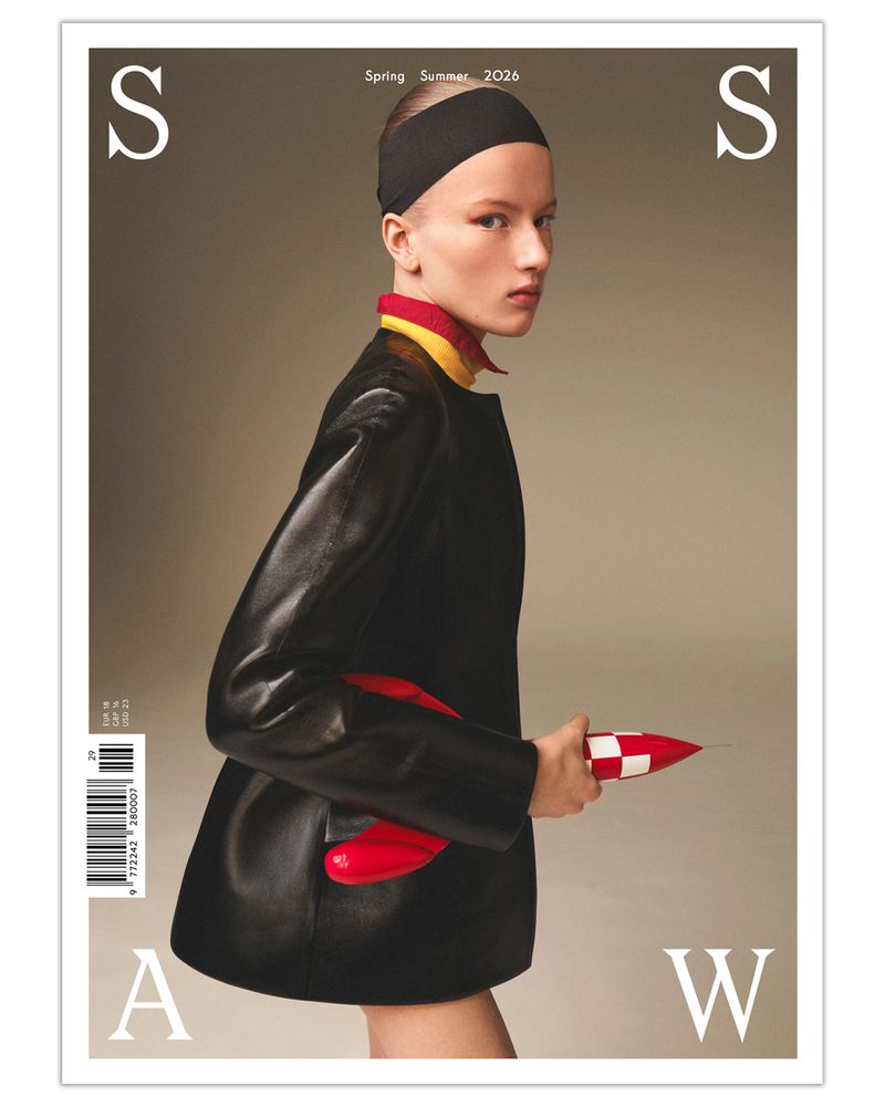 Model in black leather jacket and headband holding red and white object against a neutral background for SSAW Magazine