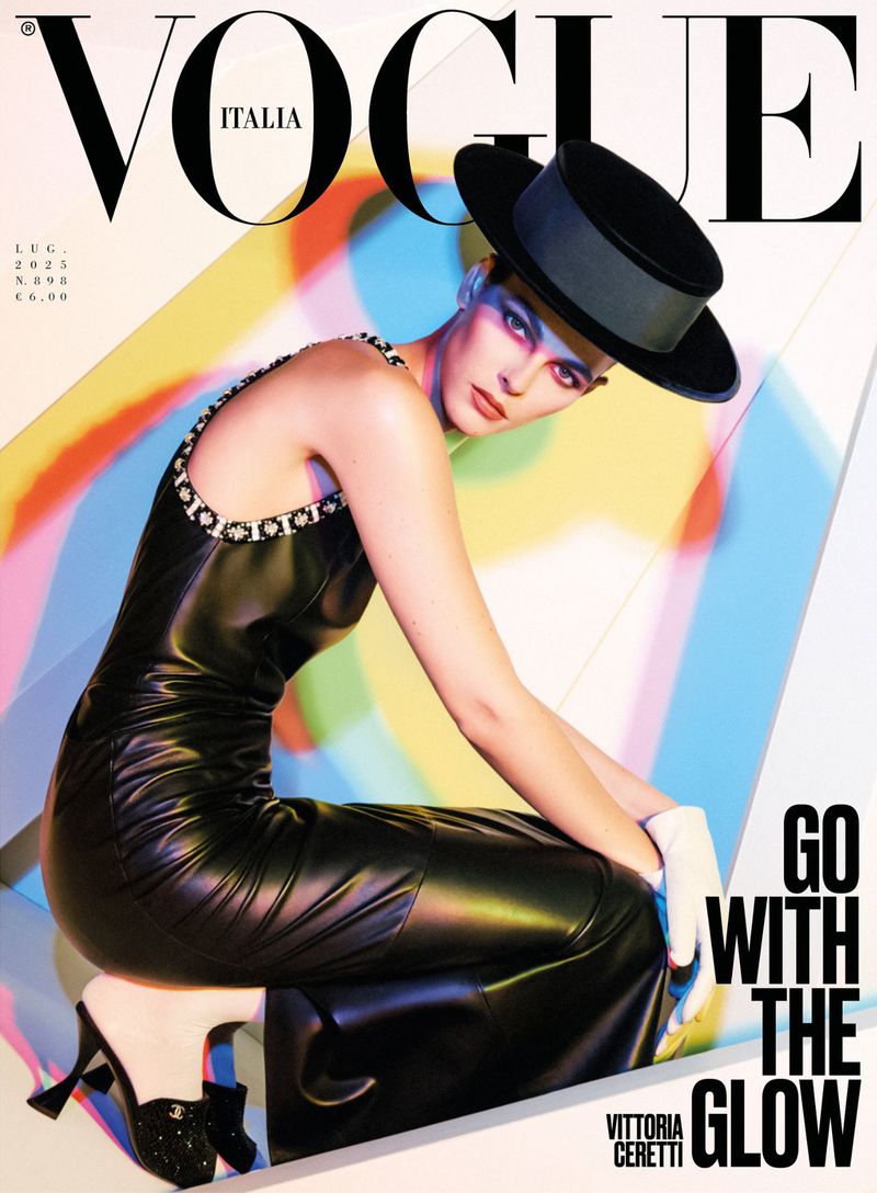 Vittoria Ceretti on Vogue Italia magazine cover, modeling black leather dress and hat against colorful geometric background.