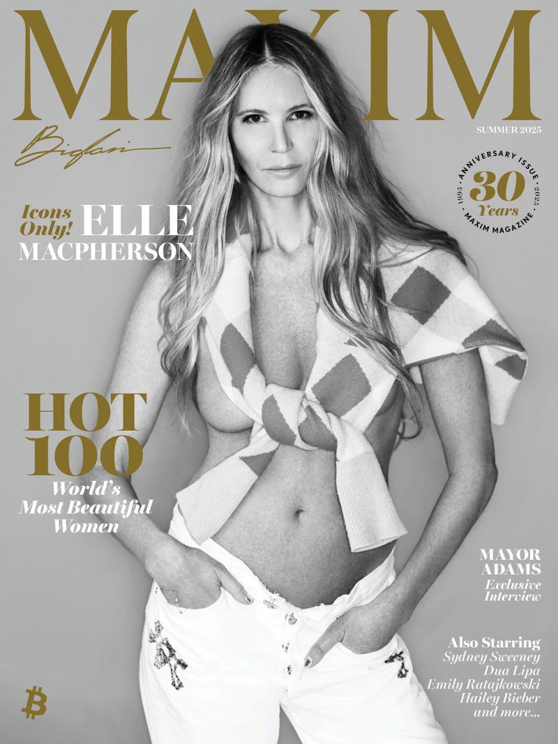 Elle Macpherson graces a Maxim cover in a medium shot, showcasing a casual pose, white jeans, and a tied sweater, set against a neutral background.