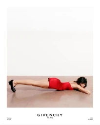 Kaia Gerber lying flat in a red slip dress against a stark white studio backdrop for Givenchy F/W 2025.