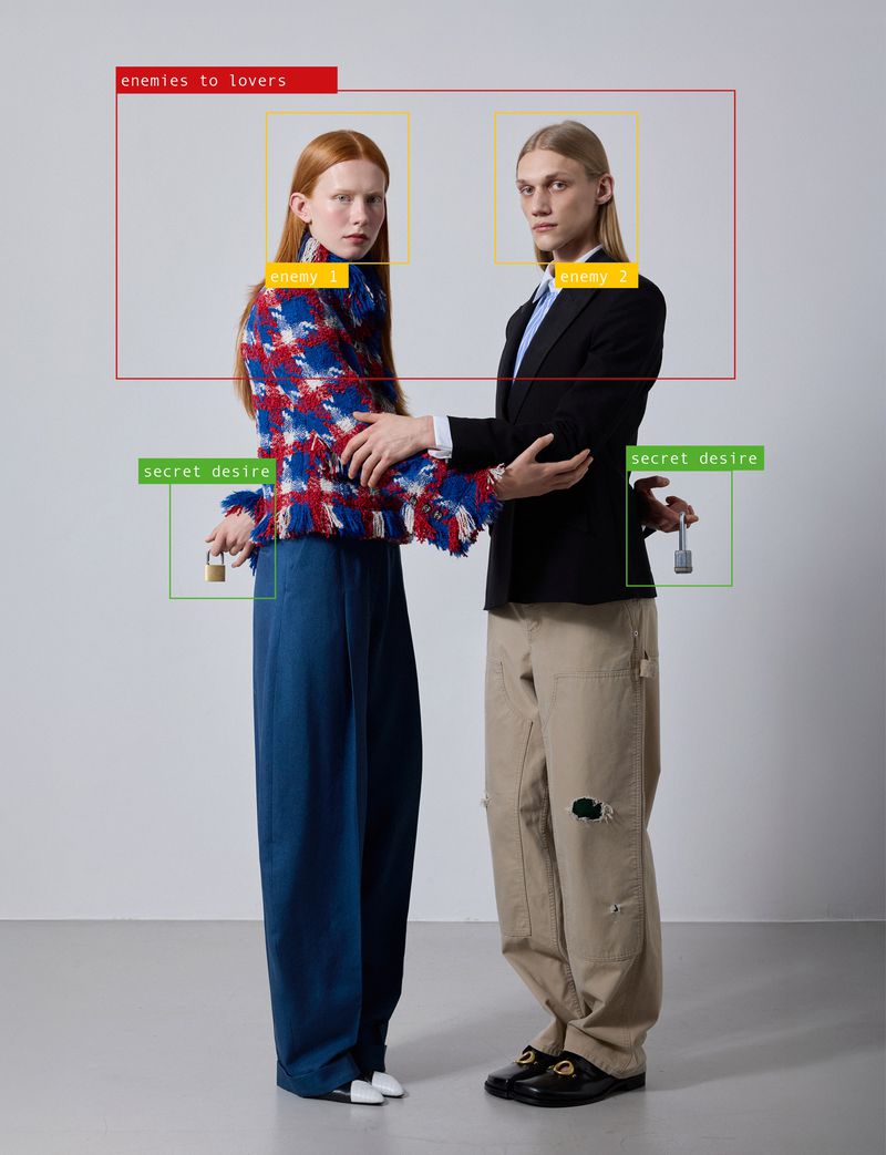 Two models standing against a neutral grey studio background holding small padlocks behind their backs.