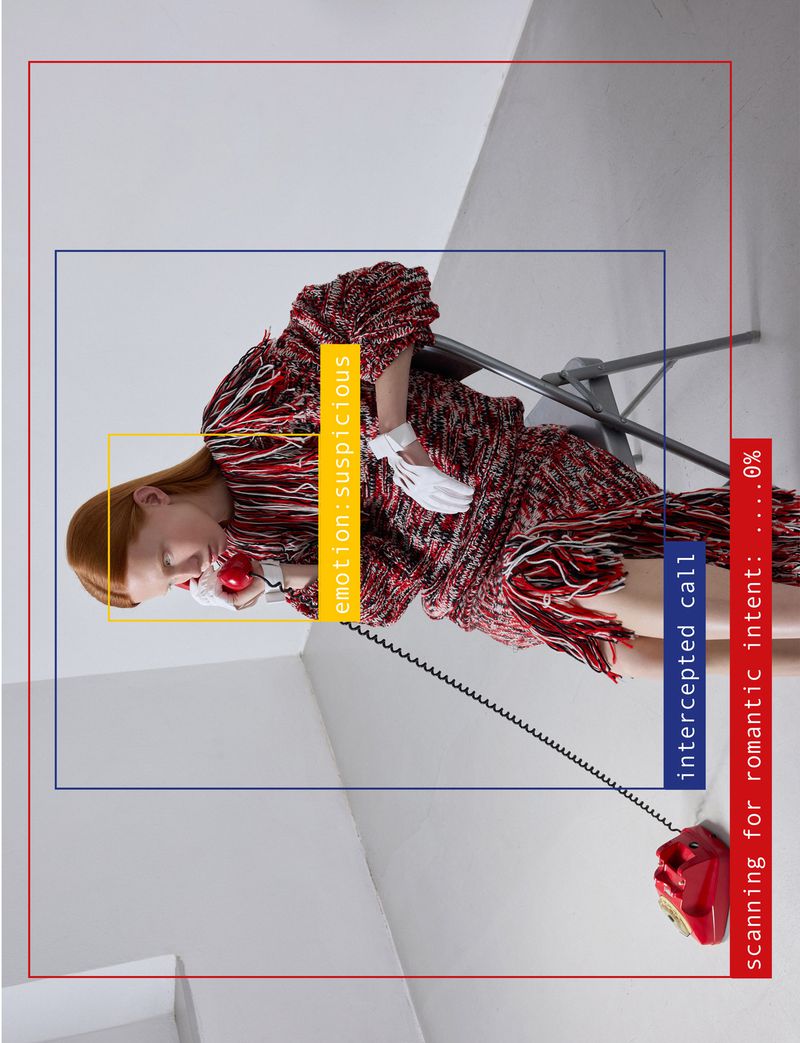 Model in red patterned dress with white gloves holding a red telephone in a minimalist white studio.