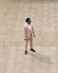 Weston McKennie wearing a pale pink suit, sunglasses, and black dress shoes, standing outdoors on stone pavement.