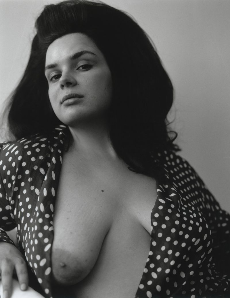 Black and white portrait of a woman with a voluminous bouffant hairstyle wearing an open polka dot blouse.