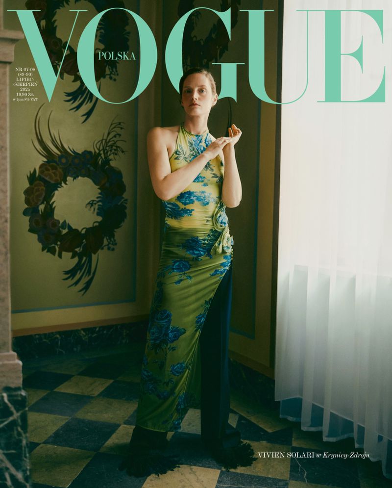 Vogue Polska cover featuring a model in a green floral dress and black pants, posing in a marble-floored interior with floral wall art.