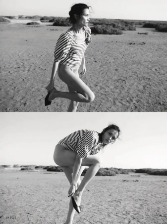 Black and white diptych of Charlotte Carey posing in a striped puff-sleeve bodysuit while putting on flat shoes on a sandy landscape.