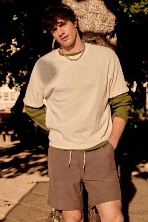 Male model leaning against a tree wearing a layered t-shirt and shorts for Zara beachwear campaign