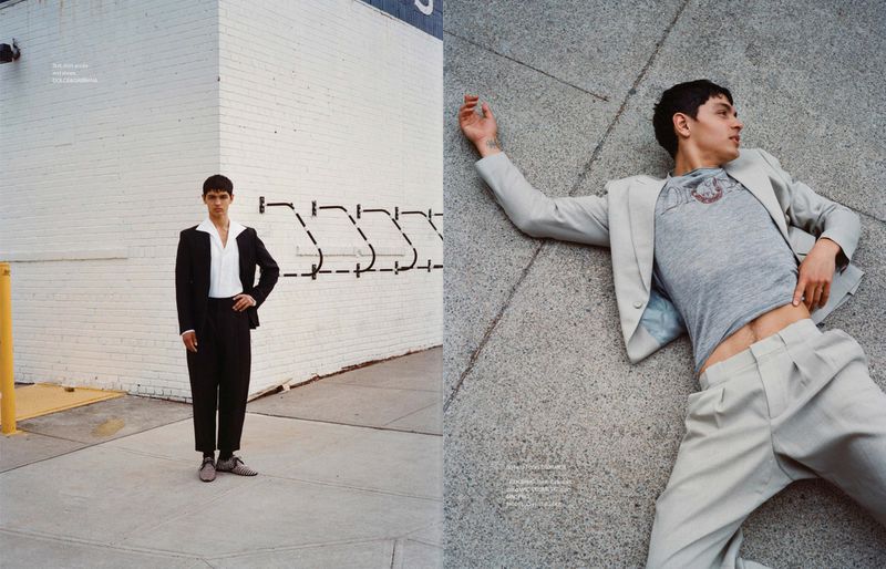 Fashion editorial: a young adult man poses in a black suit against a white brick wall, and another lies on a grey pavement wearing a blazer.