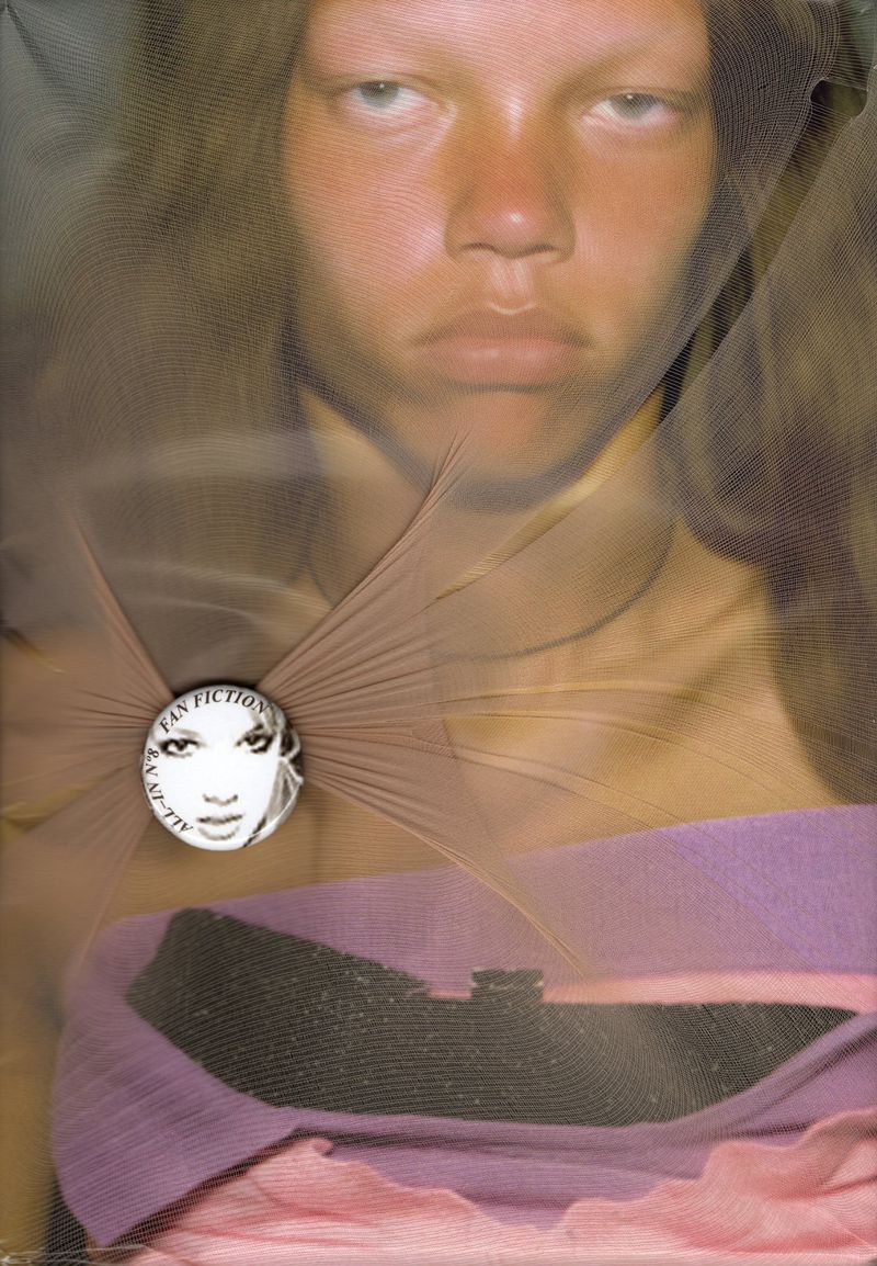 Close-up portrait of a woman with light skin and blonde hair, partially obscured by sheer fabric, wearing lavender clothing.