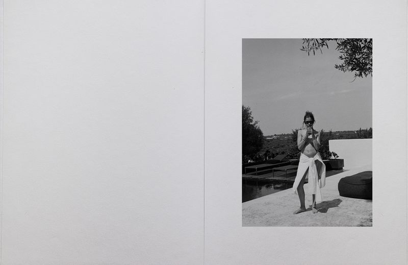 Monochrome editorial spread of a woman in sunglasses standing poolside wrapped in a white towel on a sunny terrace.