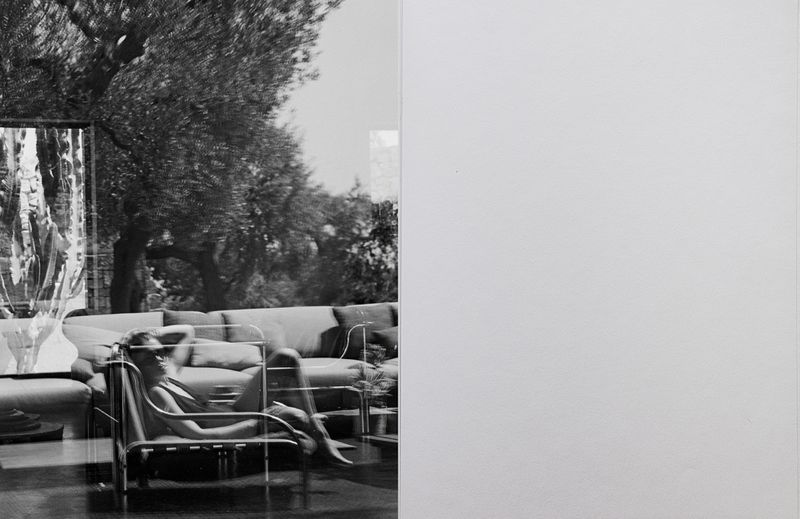 Black and white split composition featuring a person lounging on a tubular chair layered with outdoor reflections beside a blank white panel.