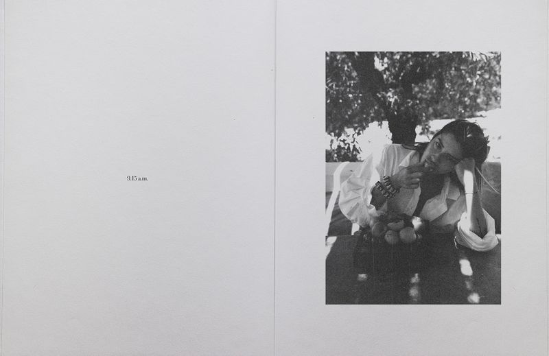 Black and white editorial spread featuring a woman in a white shirt resting her chin on her hand at an outdoor table with fruit.