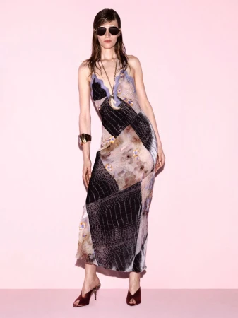 Model Leilani Mellor poses in a patchwork print slip dress, aviator sunglasses, and heeled mules against a light pink studio background.