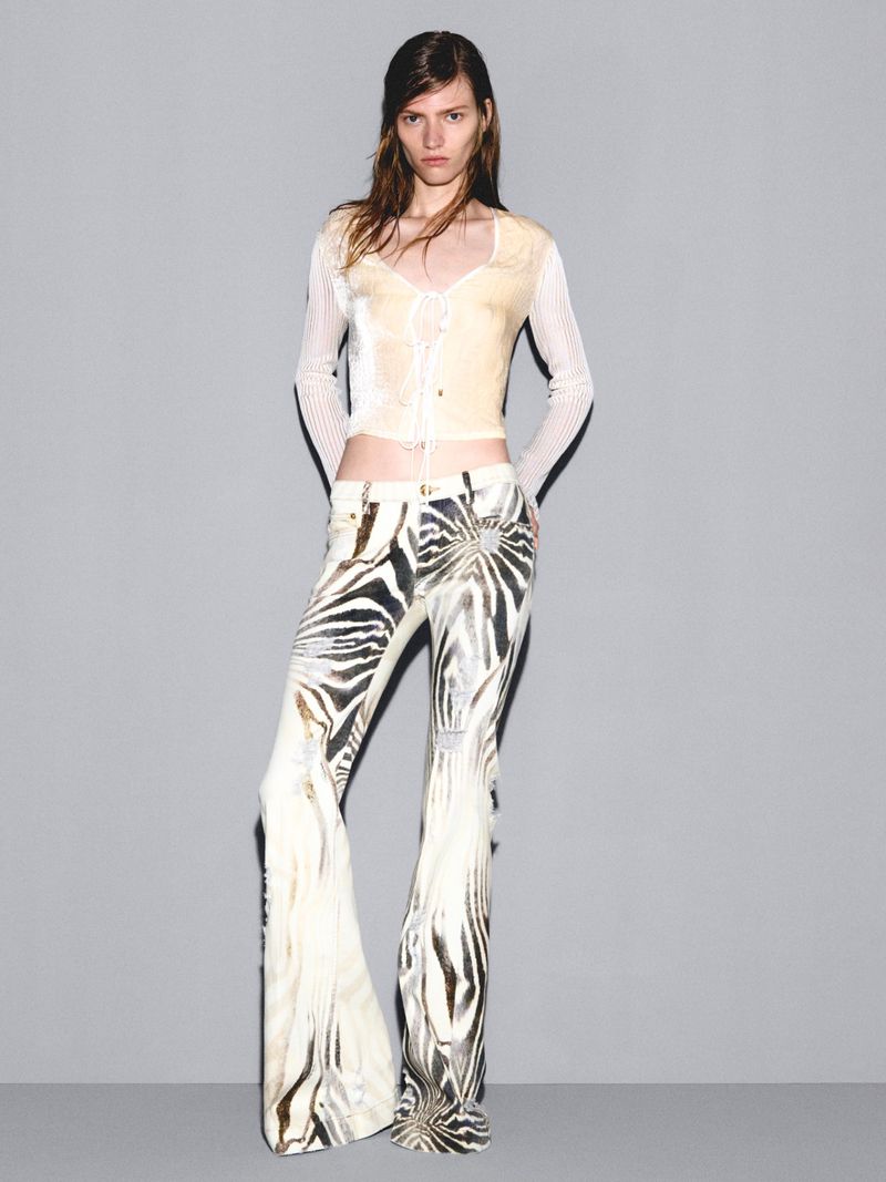 Model Leilani Mellor in a cream crop top and zebra-print flare trousers against a grey backdrop for Roberto Cavalli.