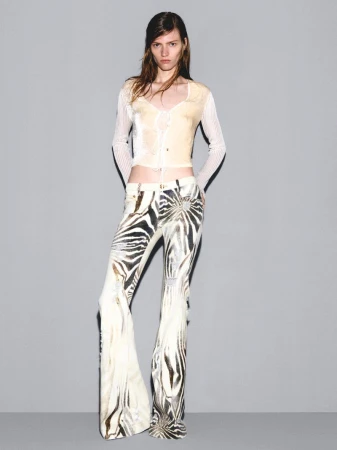 Model Leilani Mellor in a cream crop top and zebra-print flare trousers against a grey backdrop for Roberto Cavalli.