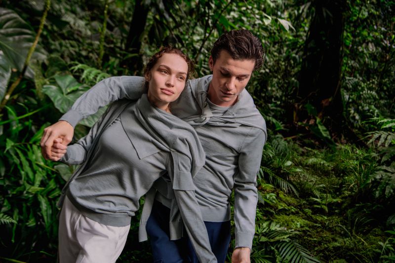 Valerie Pasker and Yulef Bopp wearing light grey knitwear amidst lush green tropical foliage for Falconeri.