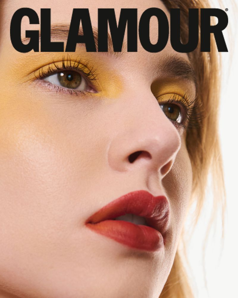 Close-up beauty portrait of a woman with yellow eyeshadow and bold red lipstick under the Glamour masthead.