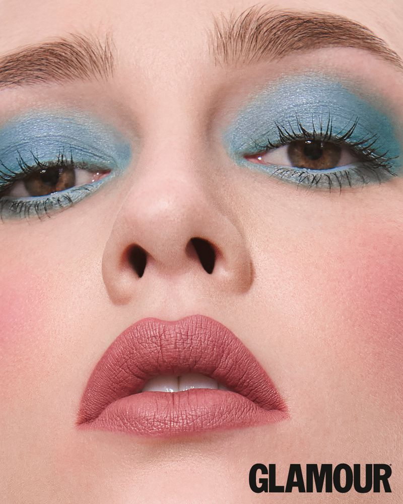 Extreme close-up beauty portrait of a woman featuring shimmering pastel blue eyeshadow and matte mauve lipstick.