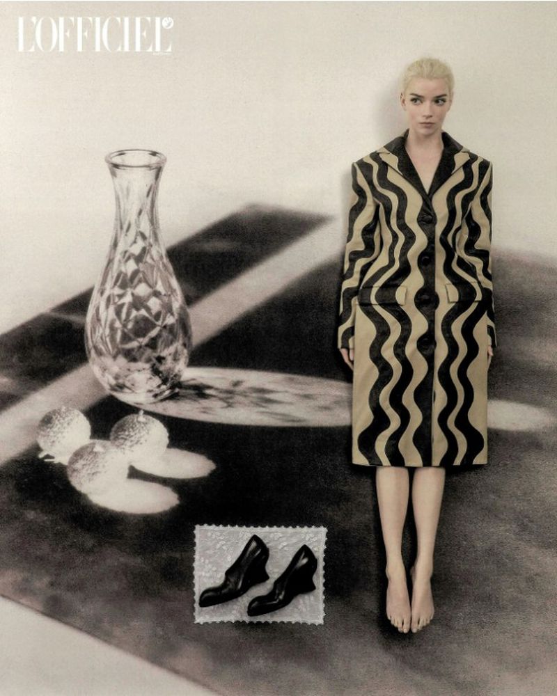 Anya Taylor-Joy wearing a patterned coat standing next to a vase on a table in an editorial photograph for L'Officiel Italia.