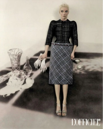 Anya Taylor-Joy in a dark plaid jacket and grey plaid skirt integrated into a surreal tabletop still life for L'Officiel Italia.