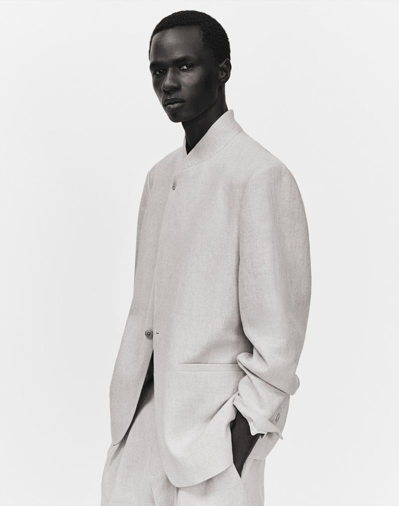 Model Malick Bodian wearing an off-white minimalist tailored suit against a pale studio backdrop for Zara Man.