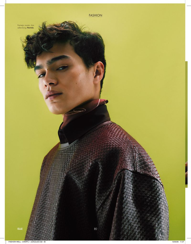 Male model wearing a textured woven sweater and high-neck scarf against a lime green background for Elle Indonesia.