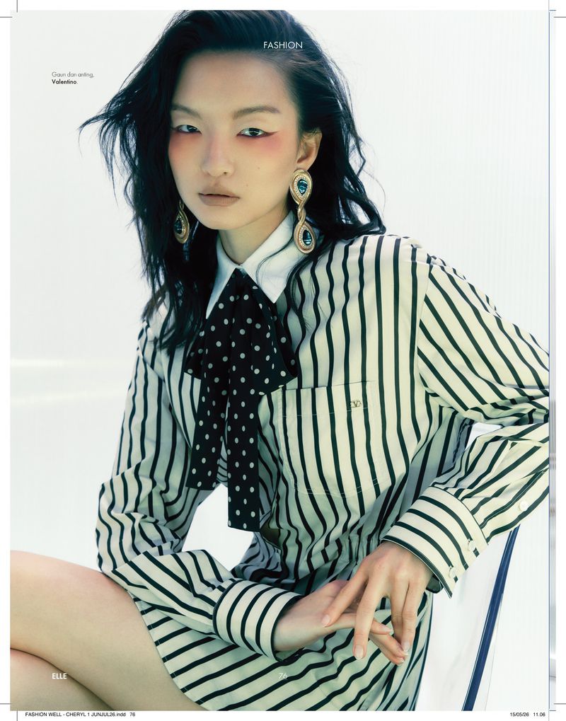 Model Shinyu Pan wearing a striped shirt dress, polka dot bow tie, and ornate drop earrings for Elle Indonesia.