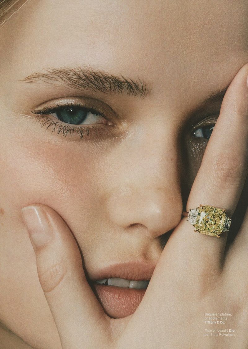 Close-up beauty portrait of a model holding a hand with a large yellow diamond ring near her face for Marie Claire France.